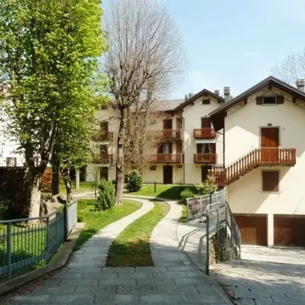 Villaggio residenziale con case bianche, giardini curati e vialetti in pietra circondati da alberi